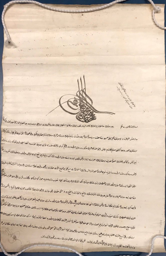 Handwritten text in Arabic script in black ink with calligraphic signature at top.