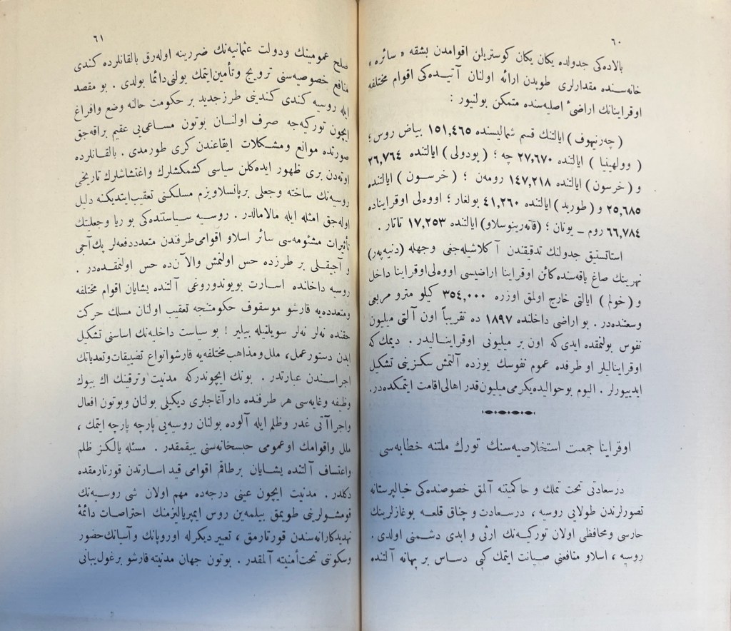 A two-page spread of white paper with black text in Arabic script, with a stylized footer towards the bottom of the right-hand page above the title of the new article.