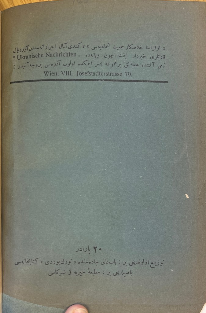 An olive-grey book cover with text in black ink in Arabic script, and a few works in Latin script, spaced at the top, middle and bottom of the page.