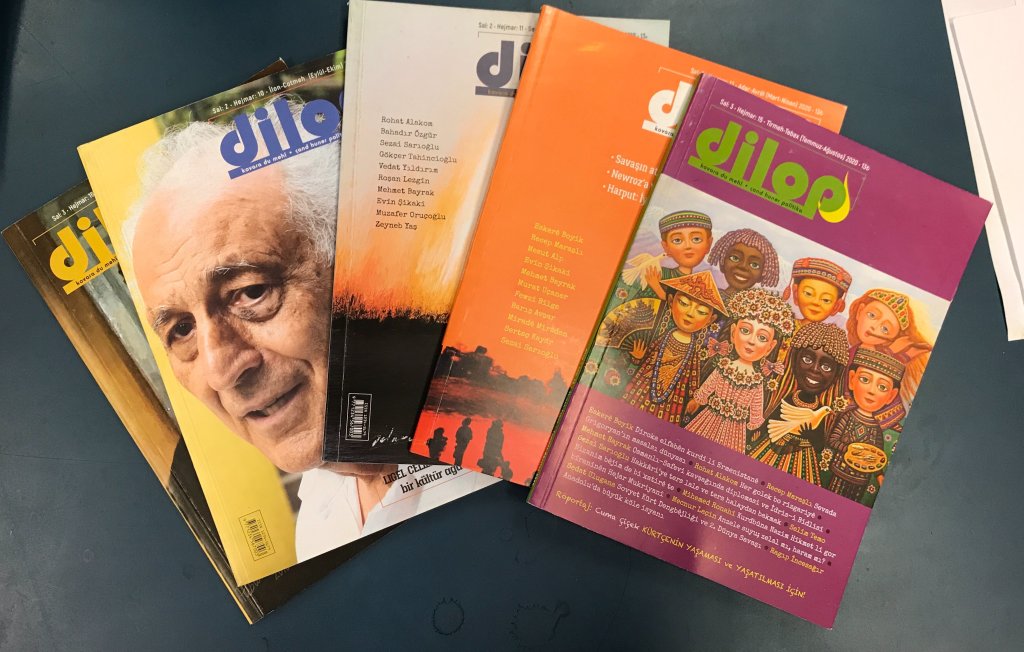 An array of multicoloured magazines splayed over a dark green table. 