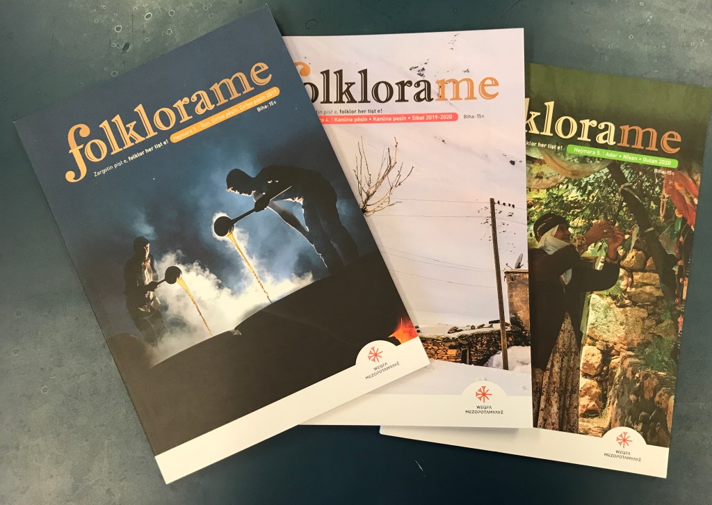 An array of multicoloured magazines splayed over a dark green table. 