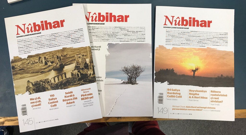 An array of multicoloured magazines splayed over a dark green table. 