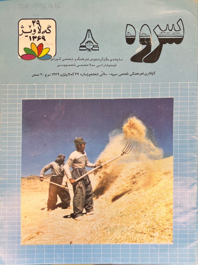 Cover of magazine with light blue background and colour photograph of men shoveling hay with pitchforks under a masthead in Arabic script in black and white in a stylized manner. 