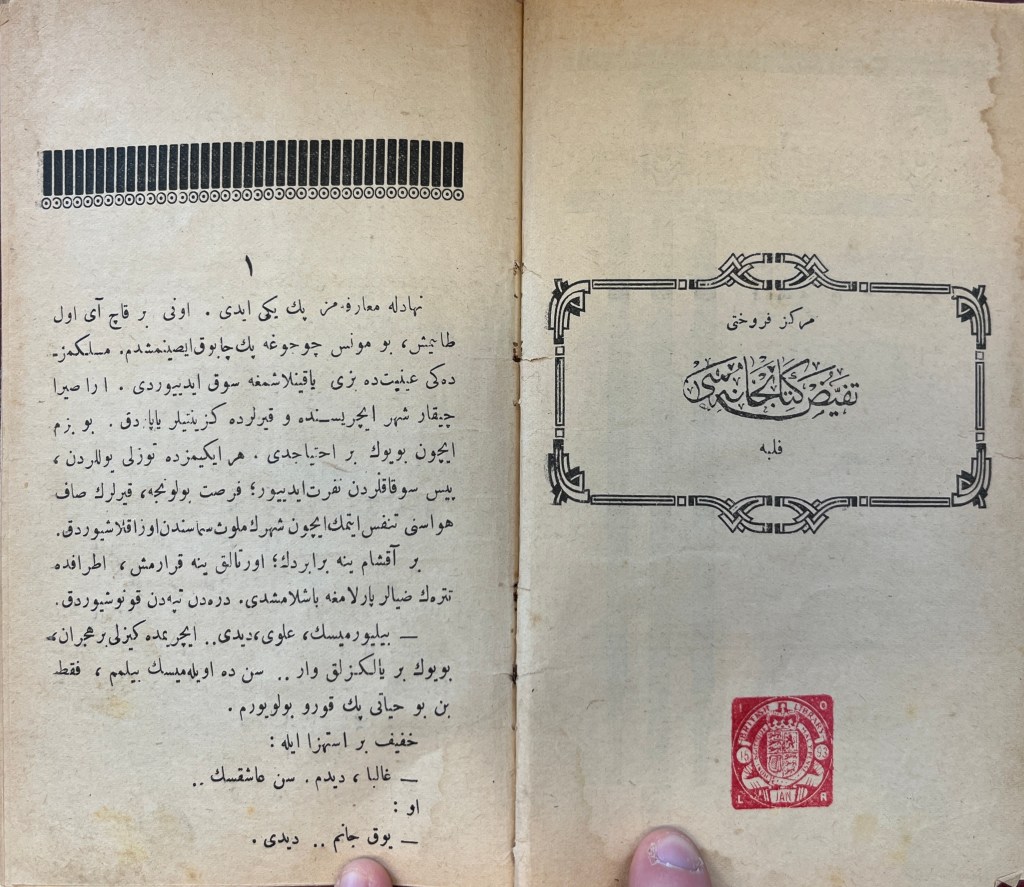 Double-page spread of white paper with black inked text in Arabic script on the left-hand page. This is topped by a row of long black rectangles packed tightly together atop a row of black circles with dots in them. On the right-hand page is a frame made of intertwining lines around text in Arabic script mimicking calligraphy.