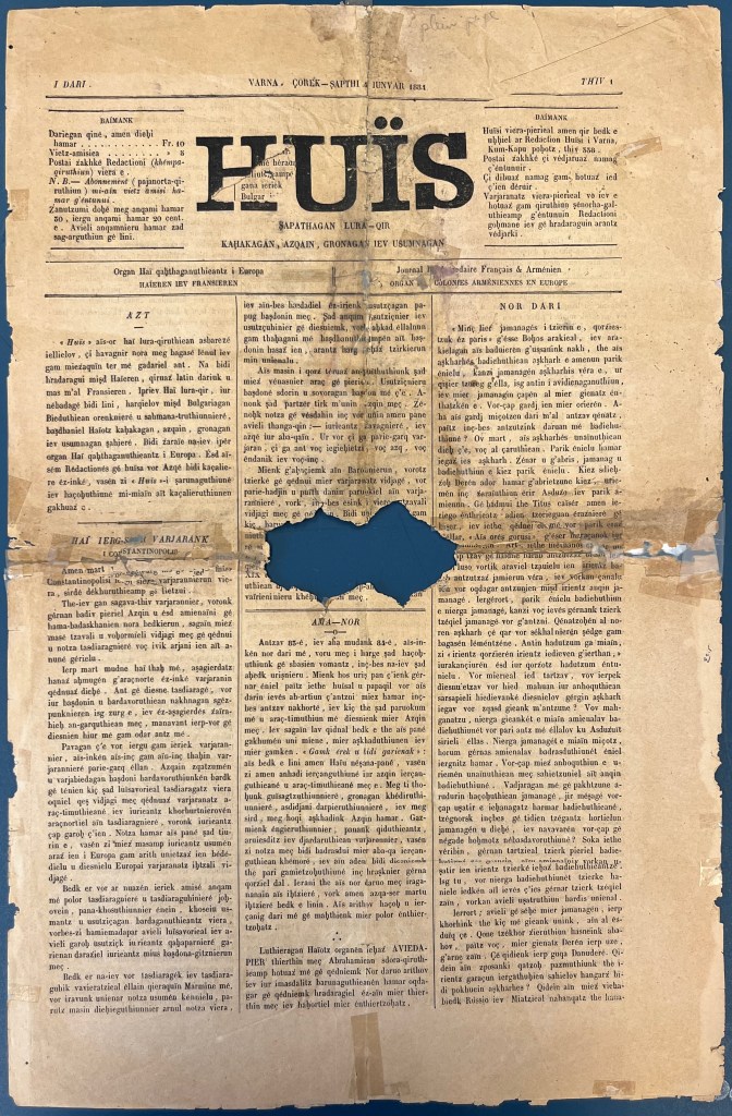 A long page of newspaper frayed at the ends and missing an oval section in the middle, printed on in black ink with Latin characters, divided into three columns, a with four large bold characters at the top in black.