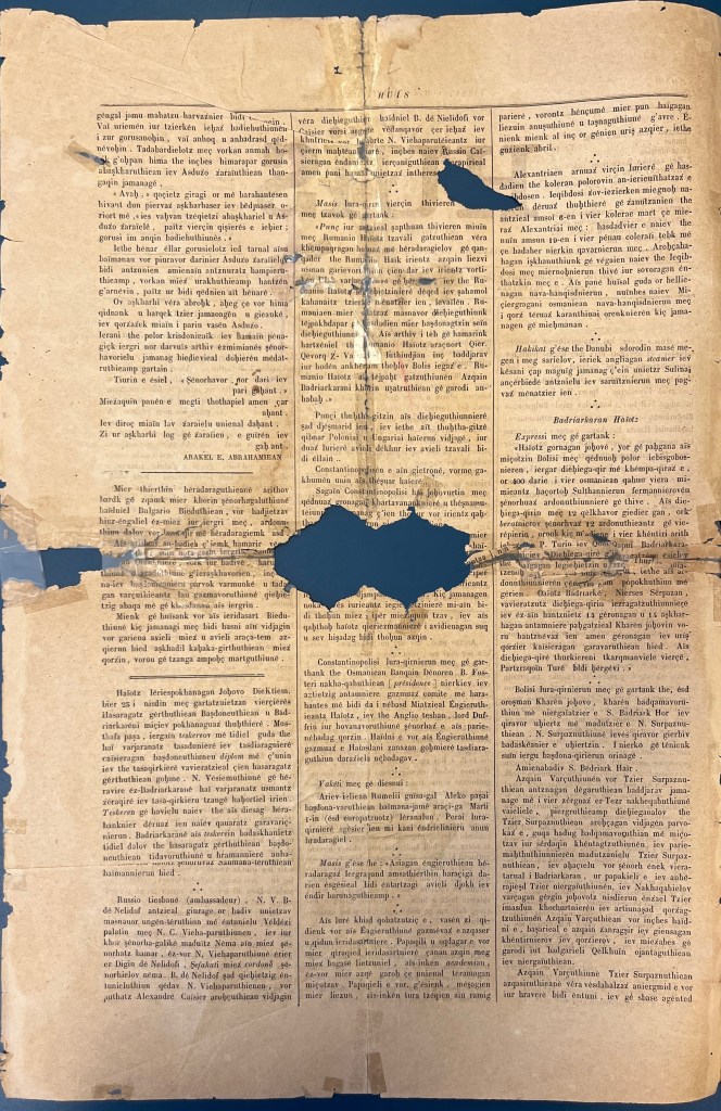A long page of newspaper frayed at the ends and missing an oval section in the middle, printed on in black ink with Latin characters, divided into three columns.