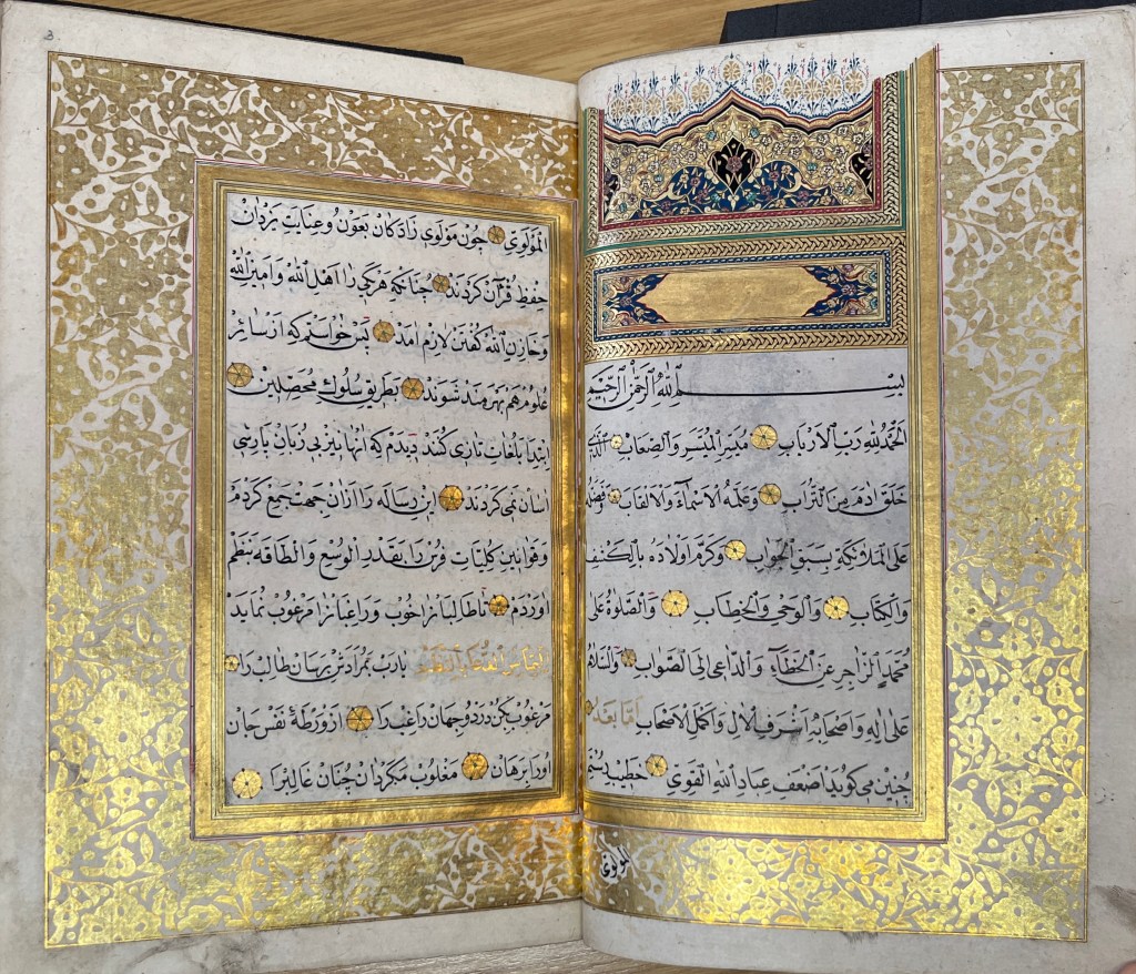 Double-page spread with gold text boxes, some of the edges of which are in vegetal form, around Arabic-script text in black ink. On the top right is a colourful section in red, blue, gold and yellow with vegetal forms