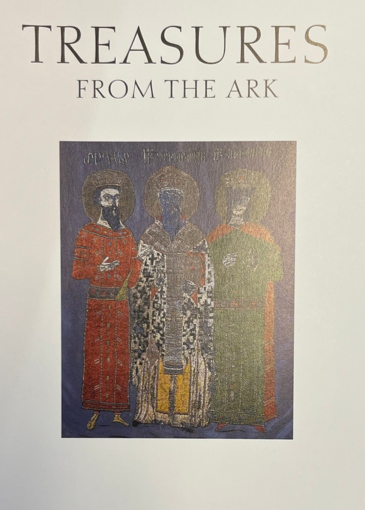 White page with large black lettering at the top and a central image of a painting of three saints with halos and a deep blue background